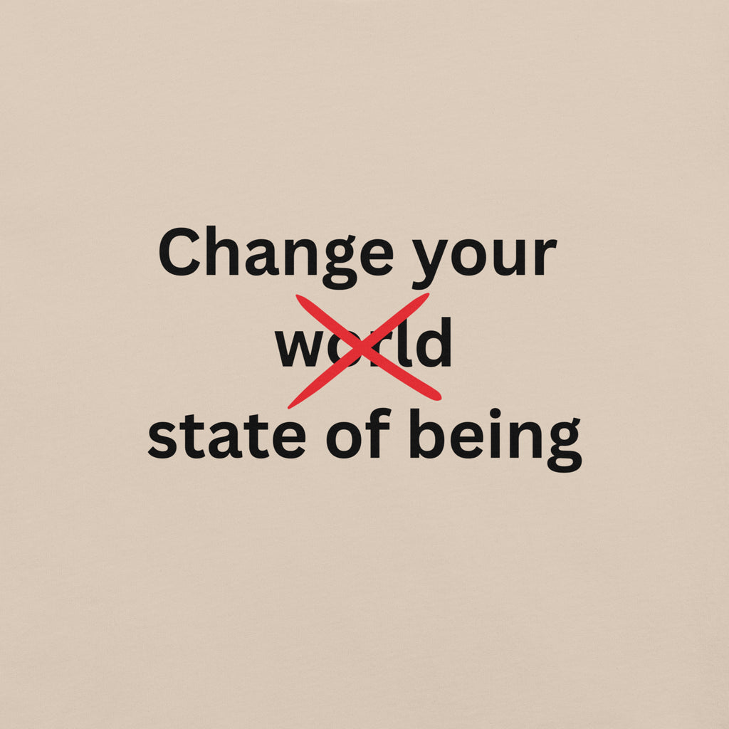 Close-up of a cream minimalist t-shirt featuring the phrase “Change your state of being” with the word “world” crossed out in red typography.