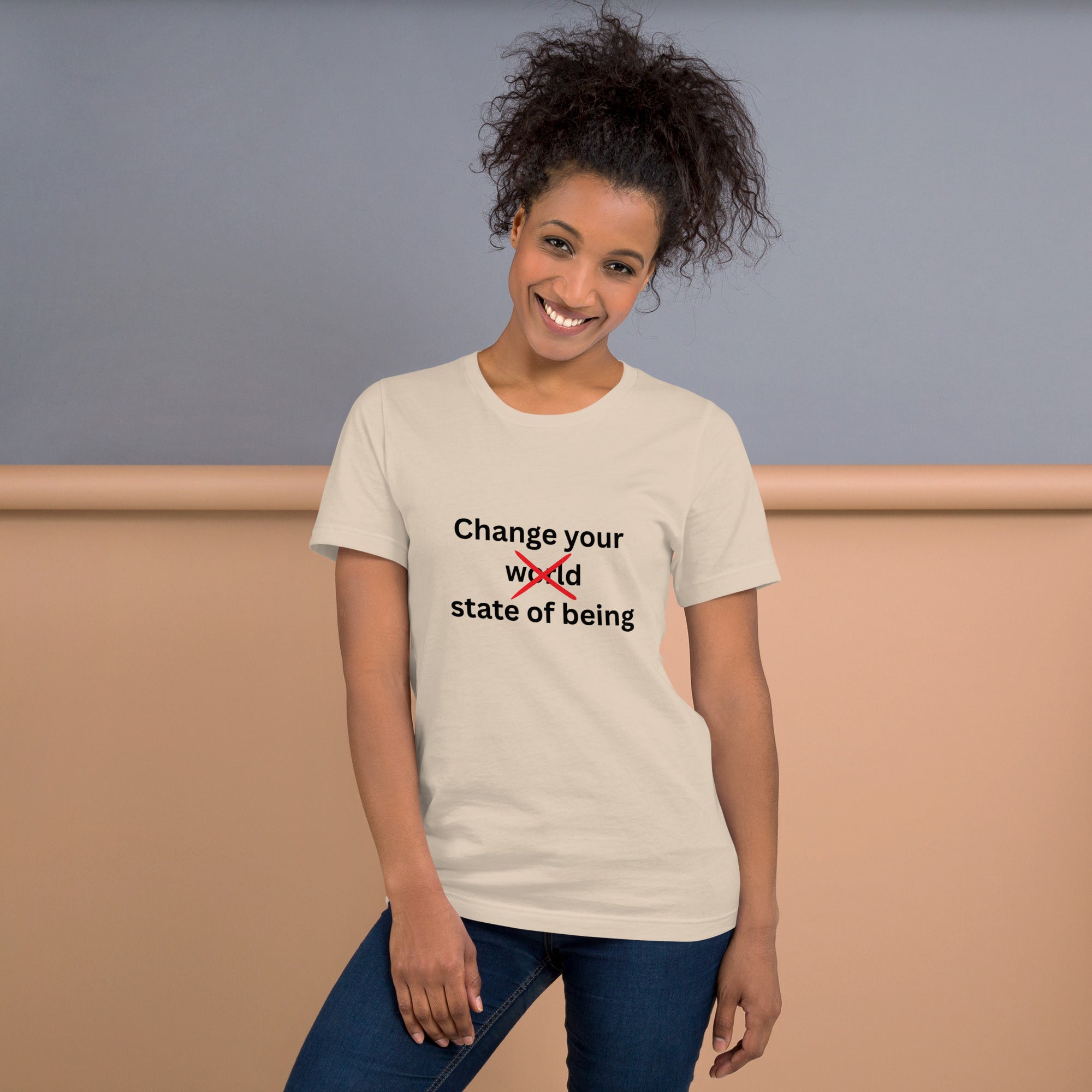 Cream t-shirt featuring the phrase “Change your state of being” with the word “world” crossed out in red minimalist typography.