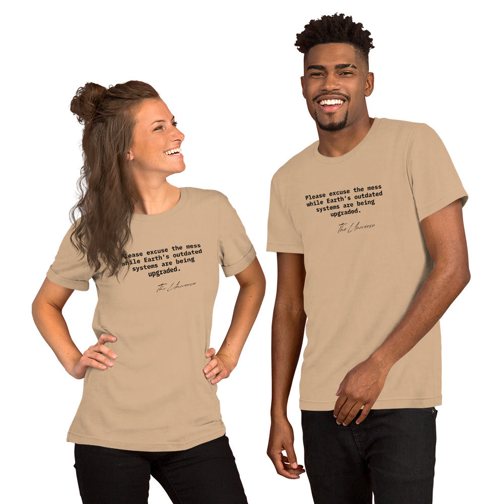 Tan unisex t-shirt featuring the phrase 'Please excuse the mess while Earth’s outdated systems are being upgraded.'