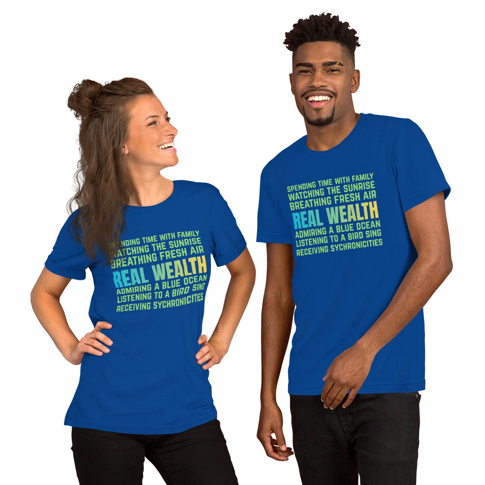 Royal blue unisex t-shirt featuring green and blue text reading “Real Wealth” with a list of lifestyle phrases.