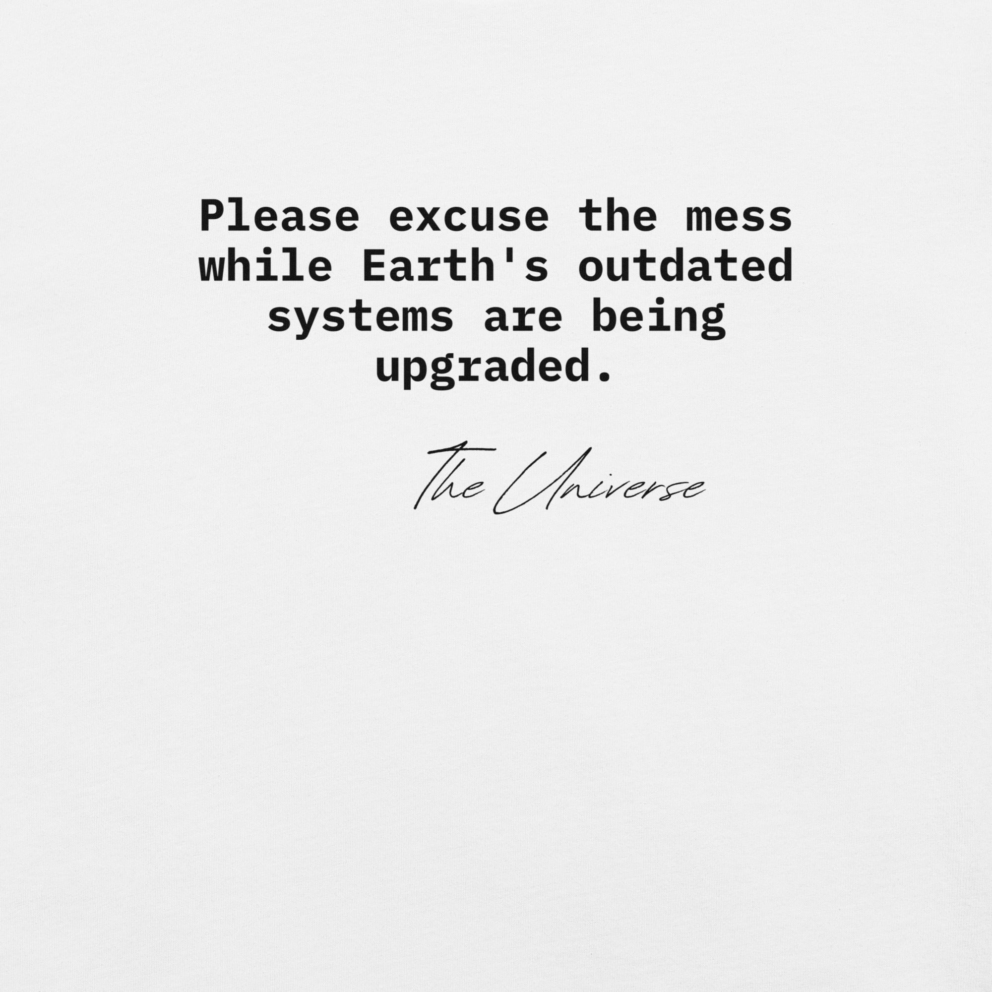 Close up of the 'Please excuse the mess while Earth’s outdated systems are being upgraded' phrase printed on the front of a unisex t-shirt.