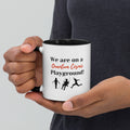 White ceramic mug with black interior and handle, featuring the phrase "We are on a Quantum Cosmic Playground." 
