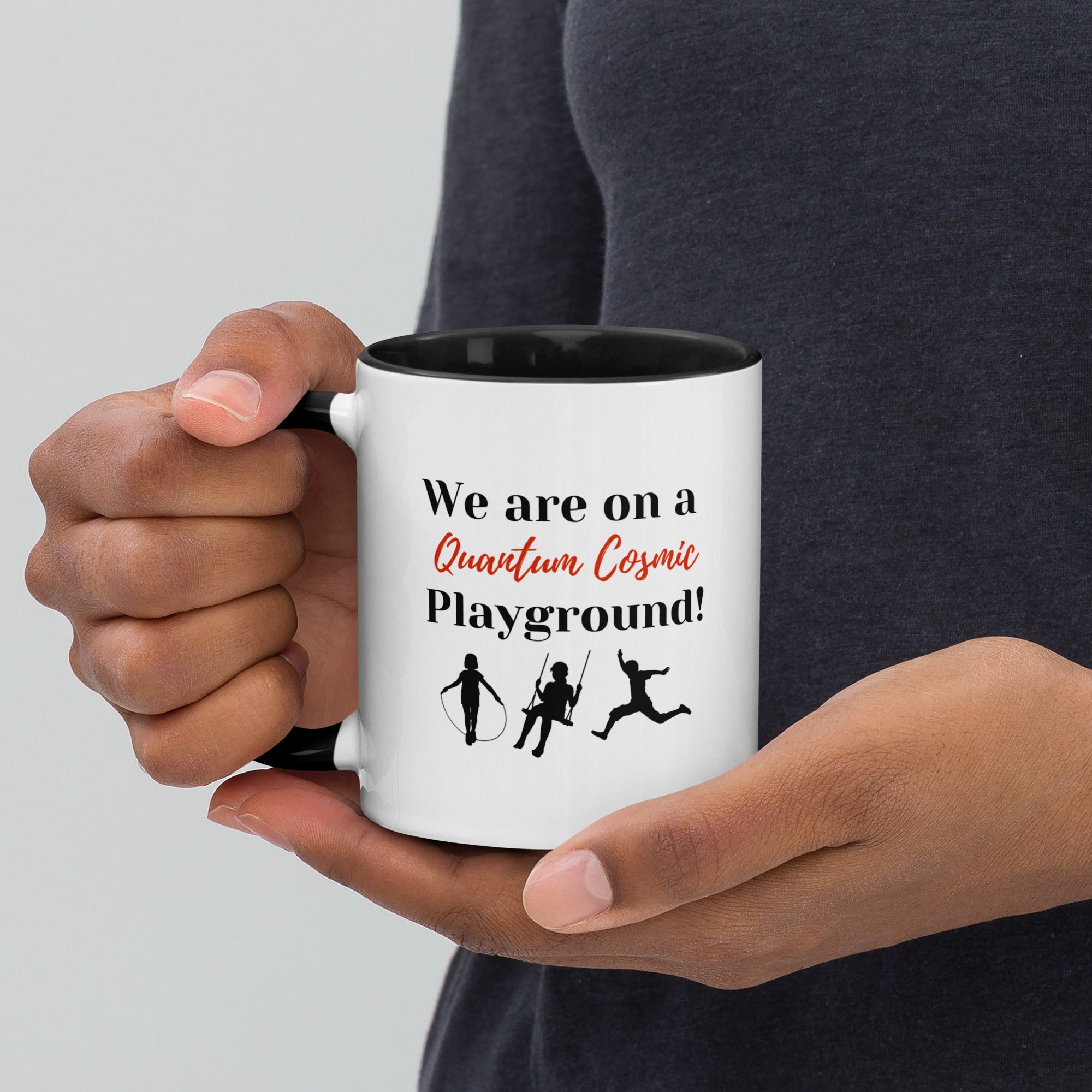 White ceramic mug with black interior and handle, featuring the phrase "We are on a Quantum Cosmic Playground." 
