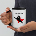 White mug with silhouette of superhero figure and red cape, bold “I am who I am” statement representing confidence and identity