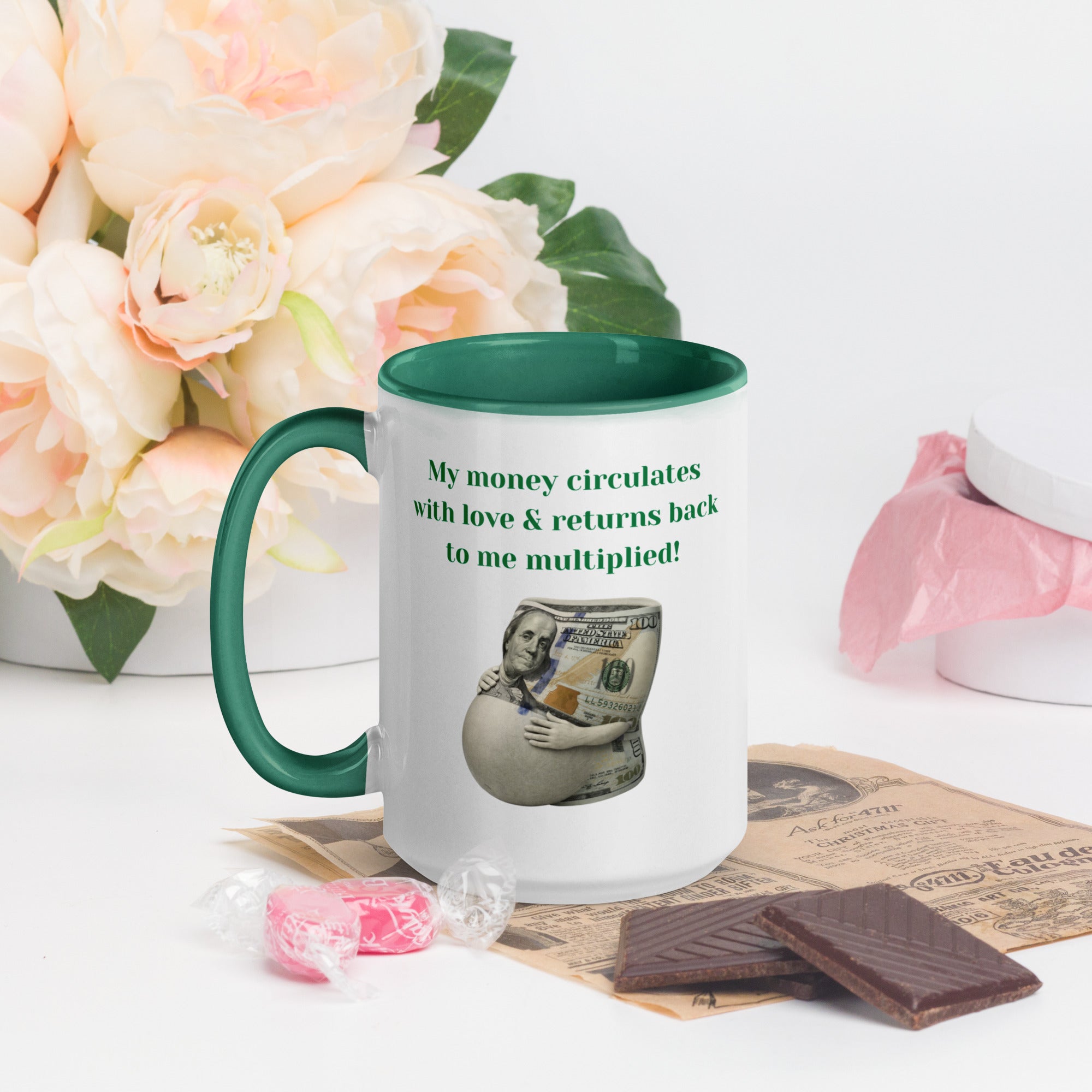 White ceramic mug with a green interior and handle, featuring the affirmation “My money circulates with love & returns back to me multiplied!” and a money illustration.