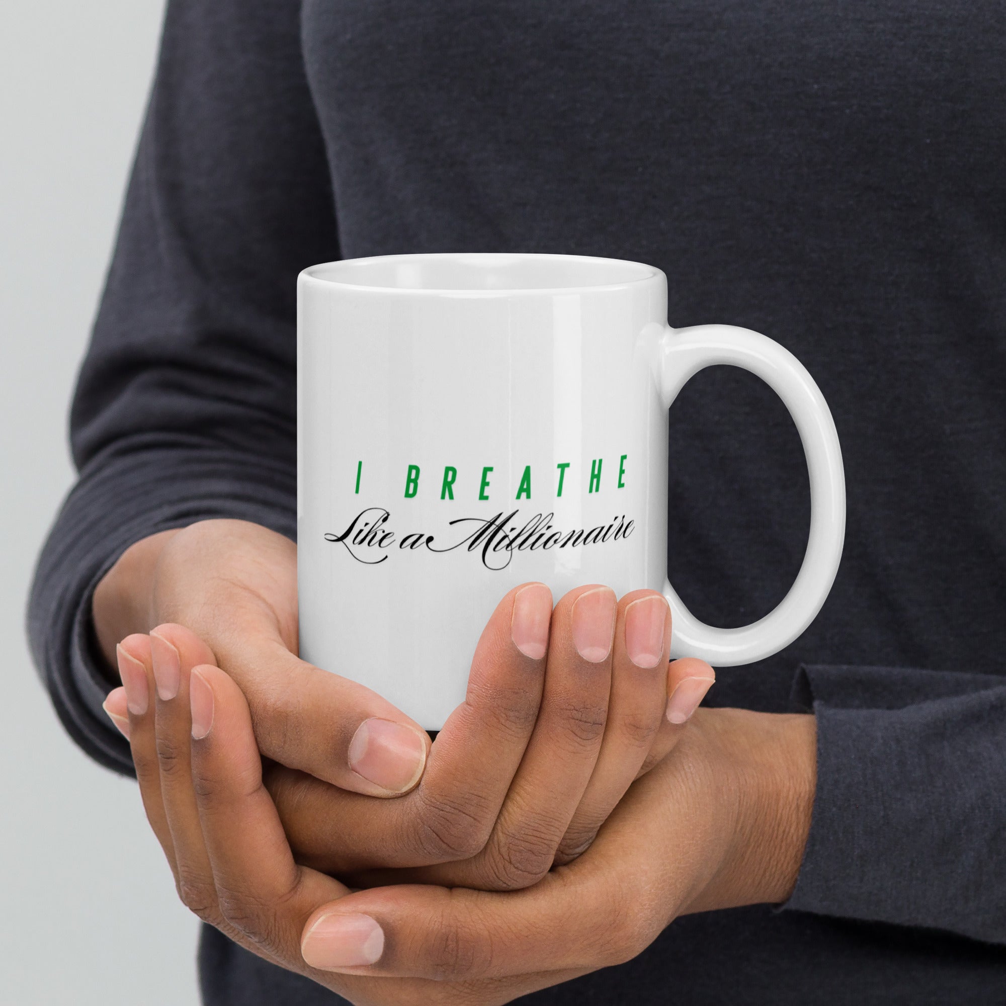 White ceramic mug featuring the phrase "I Breathe Like a Millionaire."
