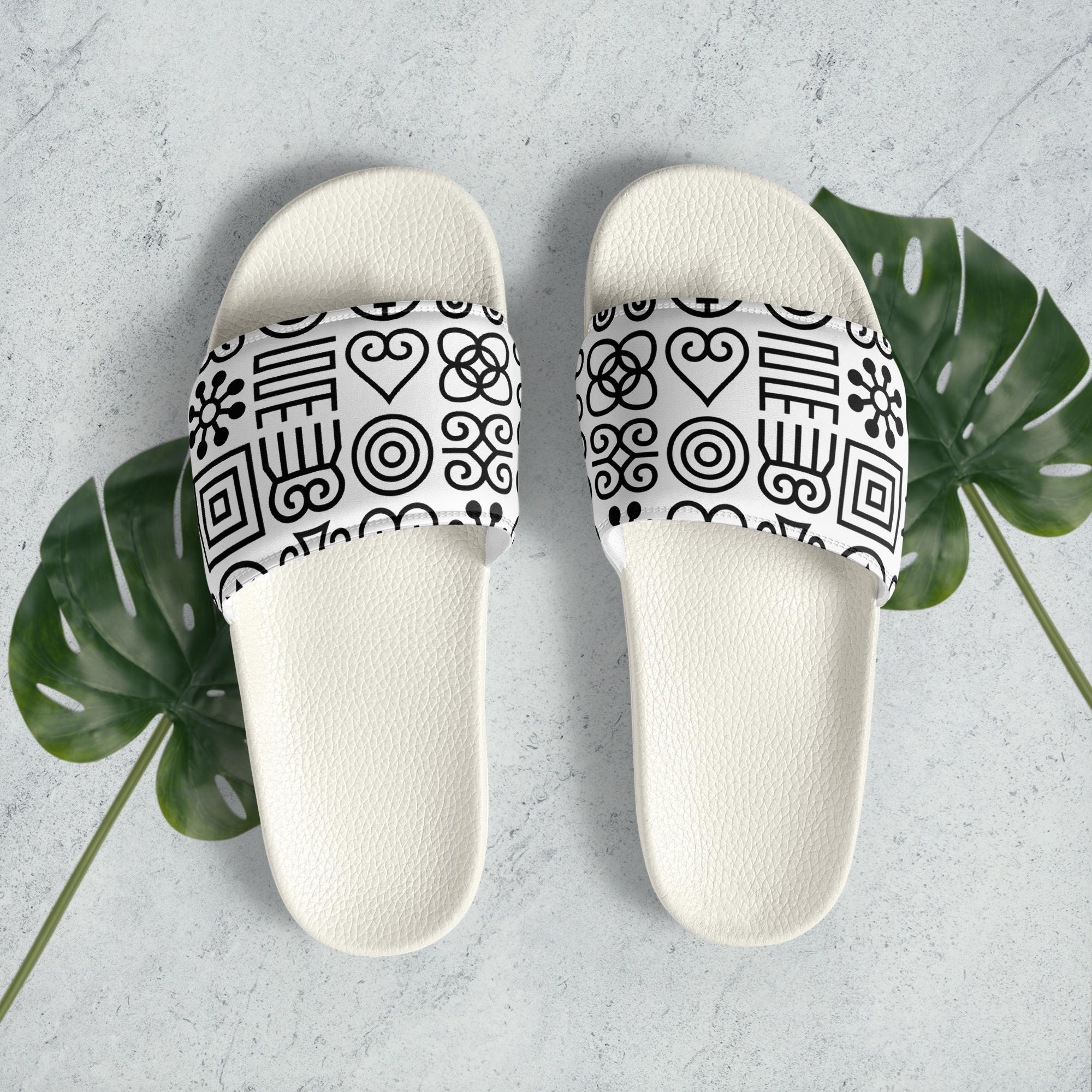 Minimalist Adinkra symbol slides displayed on a neutral surface with green leaves, representing intentional living, cultural symbolism, and everyday comfort